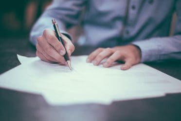 une personne tenant un stylo, signant un document ou concluant un contrat